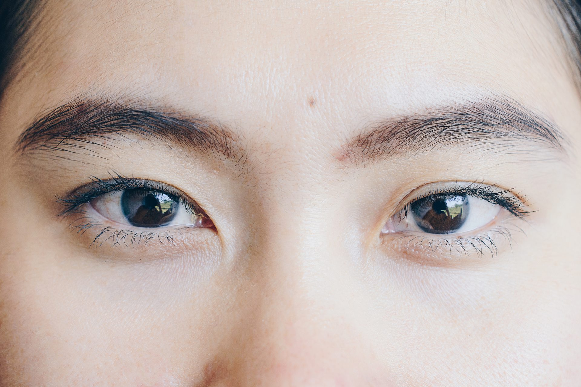 Close up shot of young Asian woman face, open her eyes and looking to the camera.